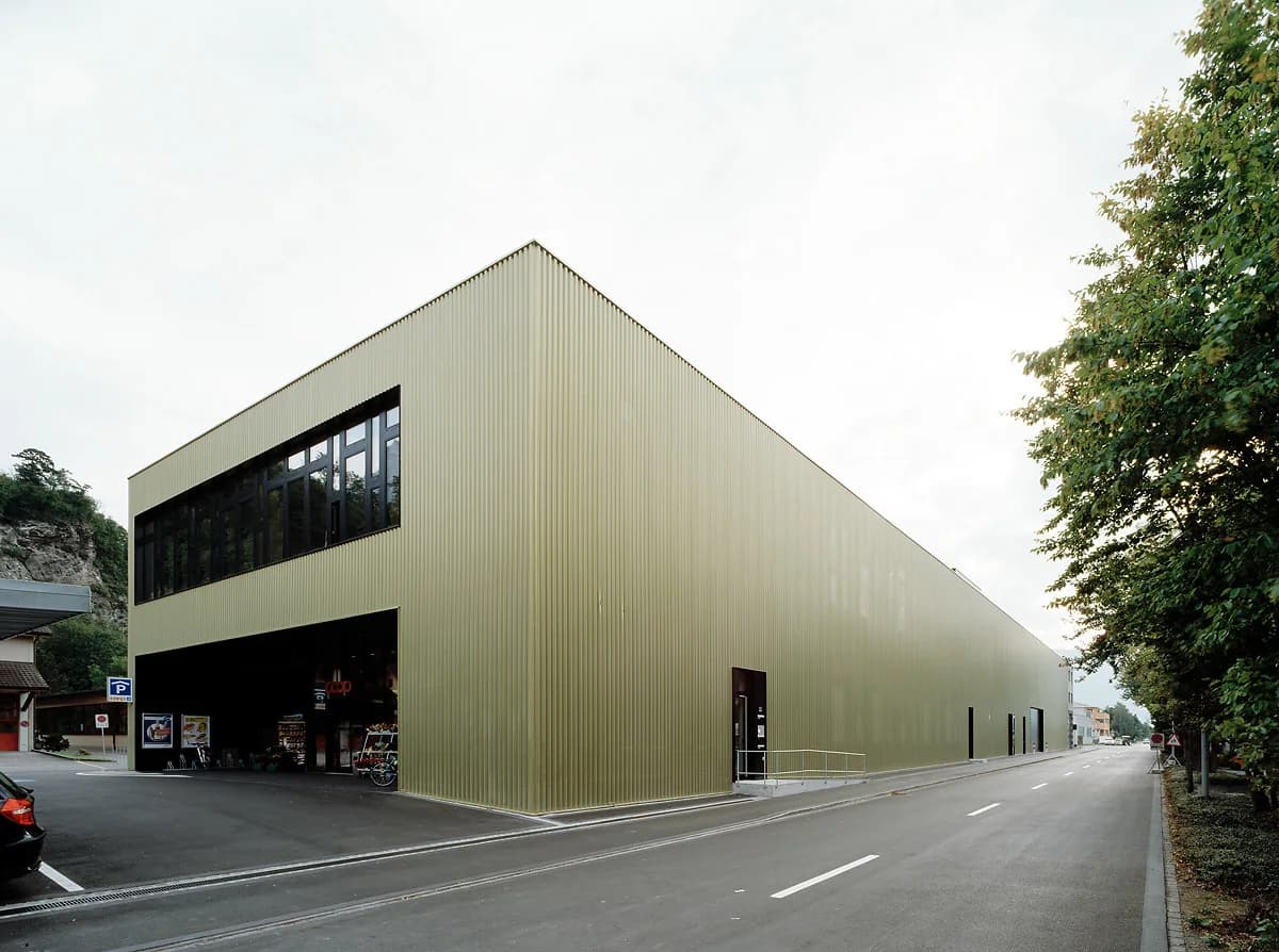 Gold-clad industrial building beside a tree-lined road