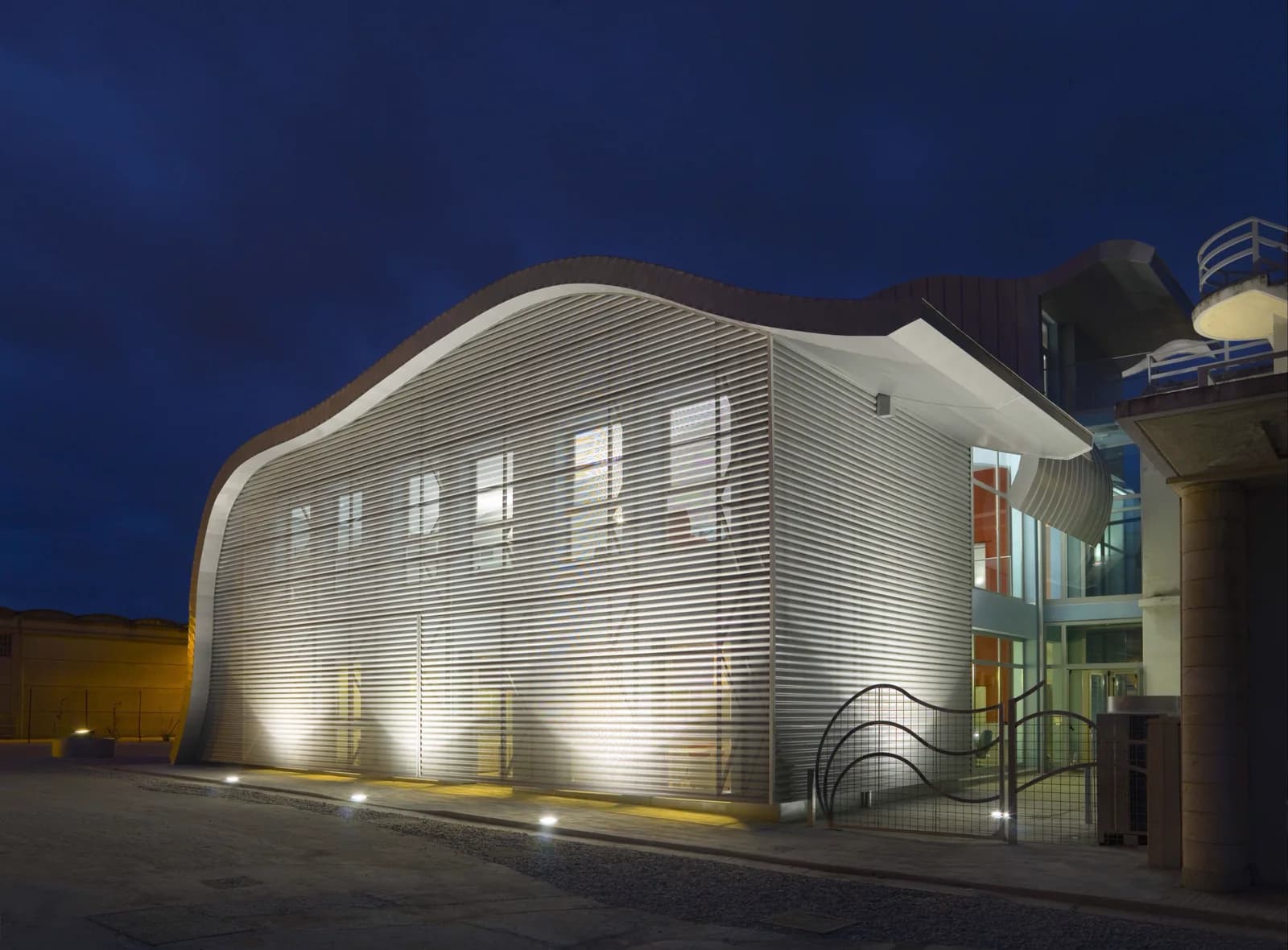 Curved metal façade illuminated at night